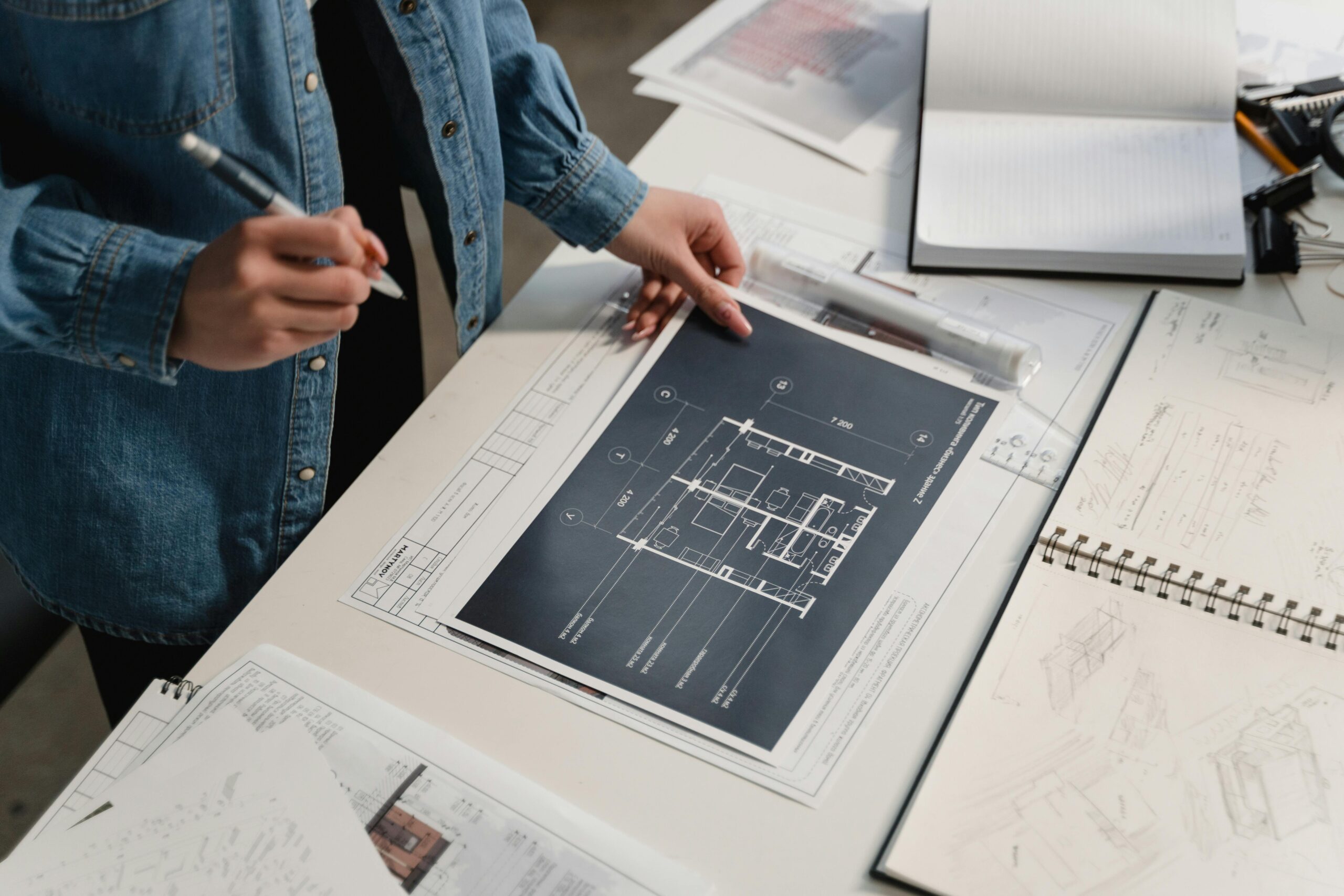 pexels-photo-6615234-6615234 Engineer reviewing architectural blueprints on a desk with technical drawings.
